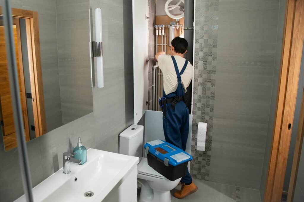 A plumber repairs plumbing in a bathroom.